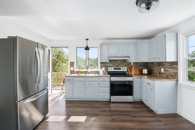 a kitchen with stainless steel appliances granite countertop a refrigerator a stove a sink and a microwave