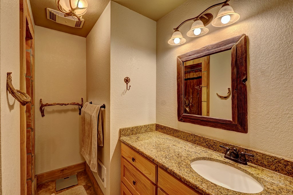 820 Bobby Shelton Ranch Road Northwest Mountain Home, TX 78058 - Photo 52 of 85 a bathroom with a granite countertop sink a mirror and a shower