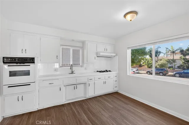 a kitchen with granite countertop white cabinets and wooden floor