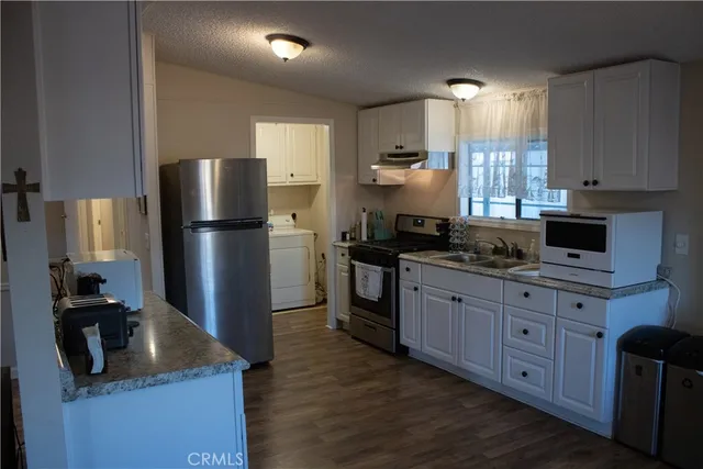a kitchen with granite countertop a refrigerator stove top oven and sink