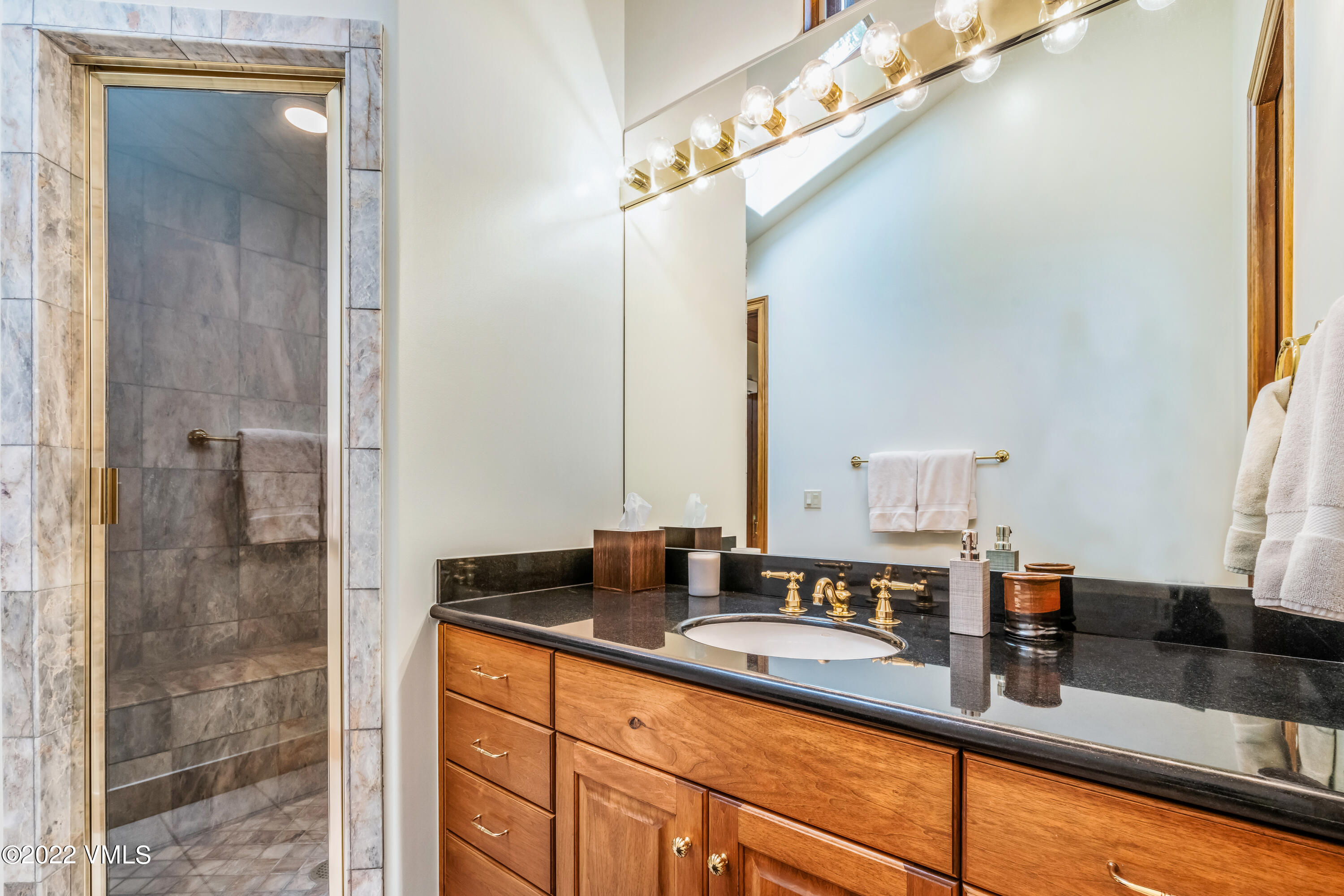 355 Forest Road, Unit B Vail, CO 81657 - Photo 23 of 36 a bathroom with a granite countertop sink a mirror and shower