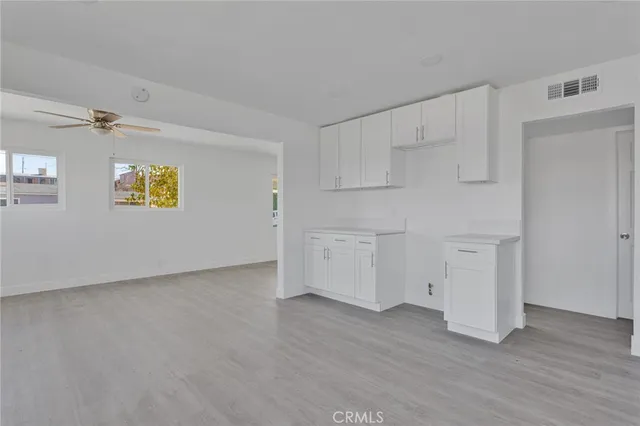 a kitchen with white cabinets and wooden floor