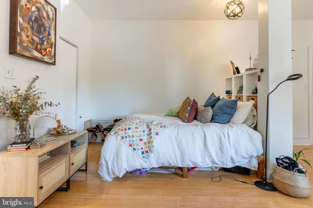 a bedroom with a bed and a potted plant on the dresser