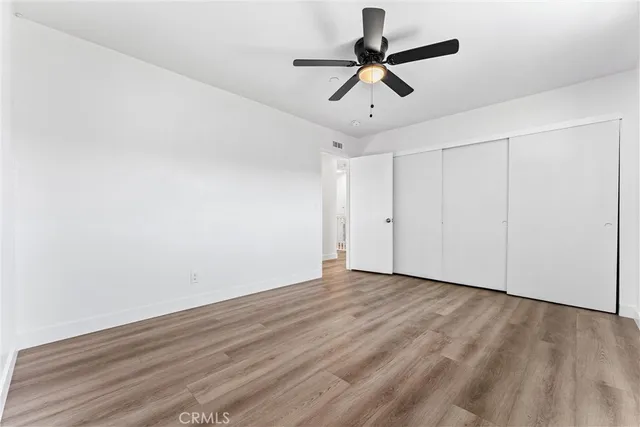 an empty room with wooden floor and ceiling fan