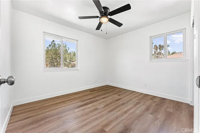 an empty room with wooden floor and a ceiling fan