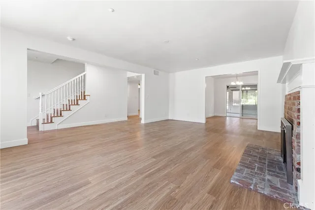 a view of an empty room with wooden floor and a fireplace
