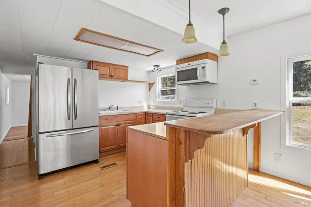 a kitchen with stainless steel appliances granite countertop a refrigerator a sink dishwasher a stove and a refrigerator with wooden floor