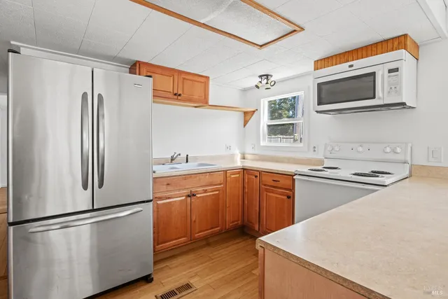 a kitchen with stainless steel appliances granite countertop a refrigerator a stove a sink and a microwave