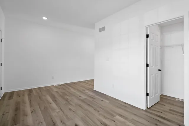 a view of an empty room with wooden floor and a bathroom