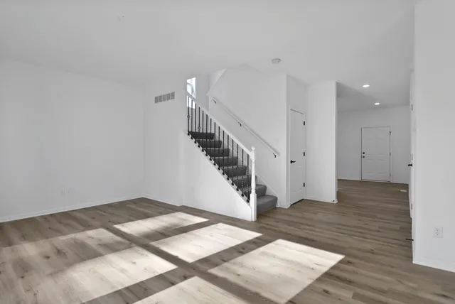 a view of an empty room with wooden floor and stairs
