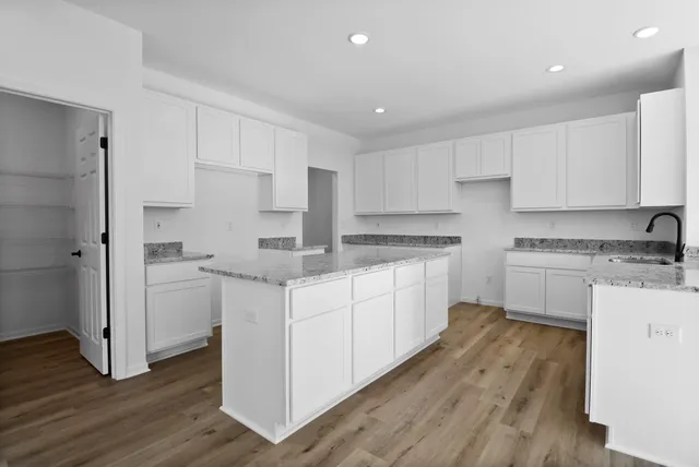 a kitchen with white cabinets stainless steel appliances and wooden floor