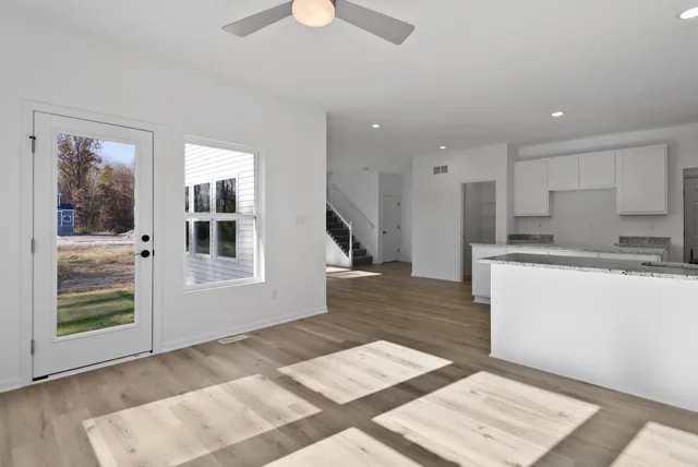a open kitchen with white cabinets and wooden floor