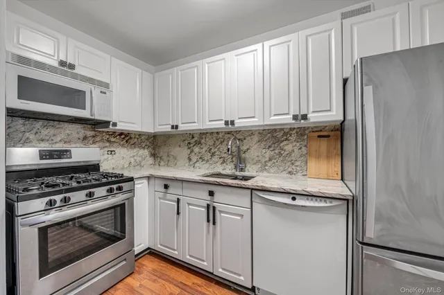 a kitchen with granite countertop white cabinets and stainless steel appliances