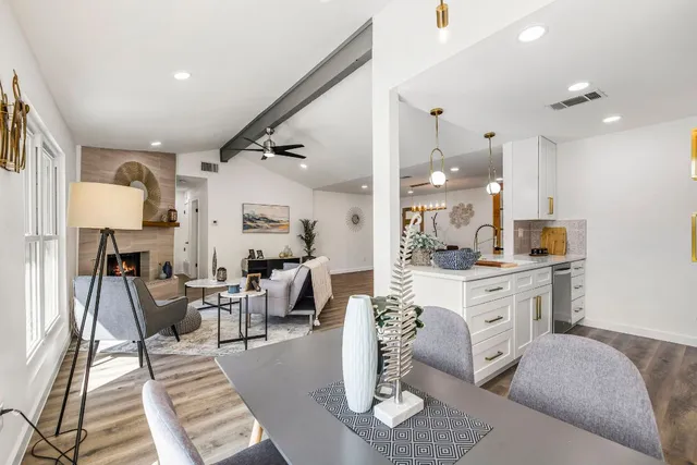 a living room with furniture a rug kitchen view and a chandelier