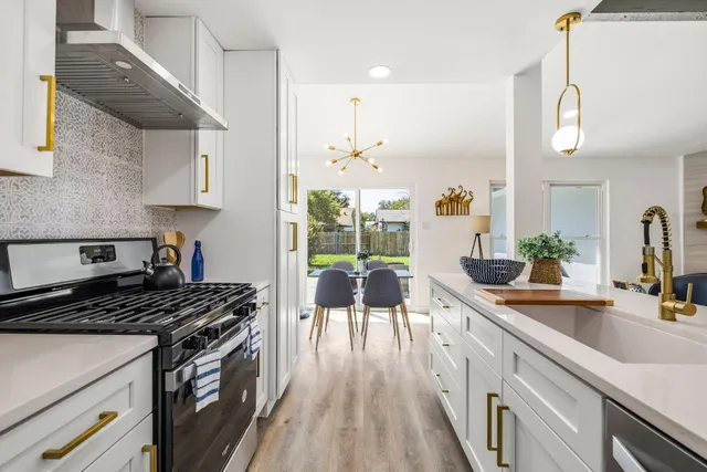 a kitchen with a stove a sink a refrigerator and wooden floor