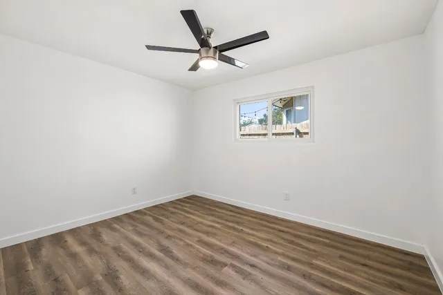 an empty room with a ceiling fan and window