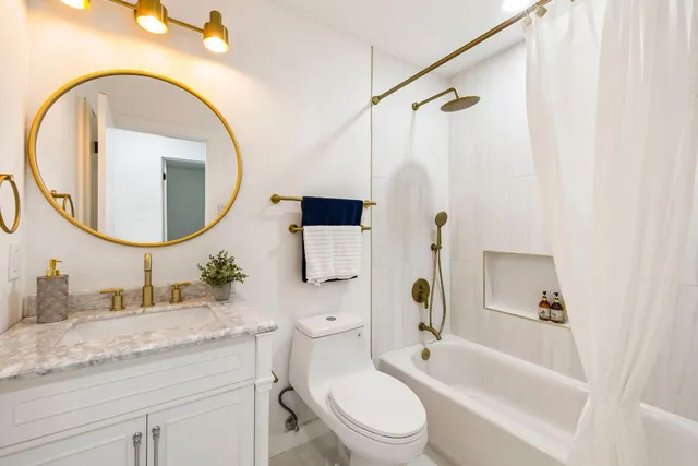 a bathroom with a granite countertop sink mirror vanity and a toilet