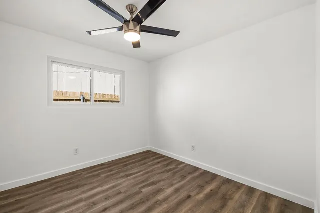 an empty room with a window and ceiling fan