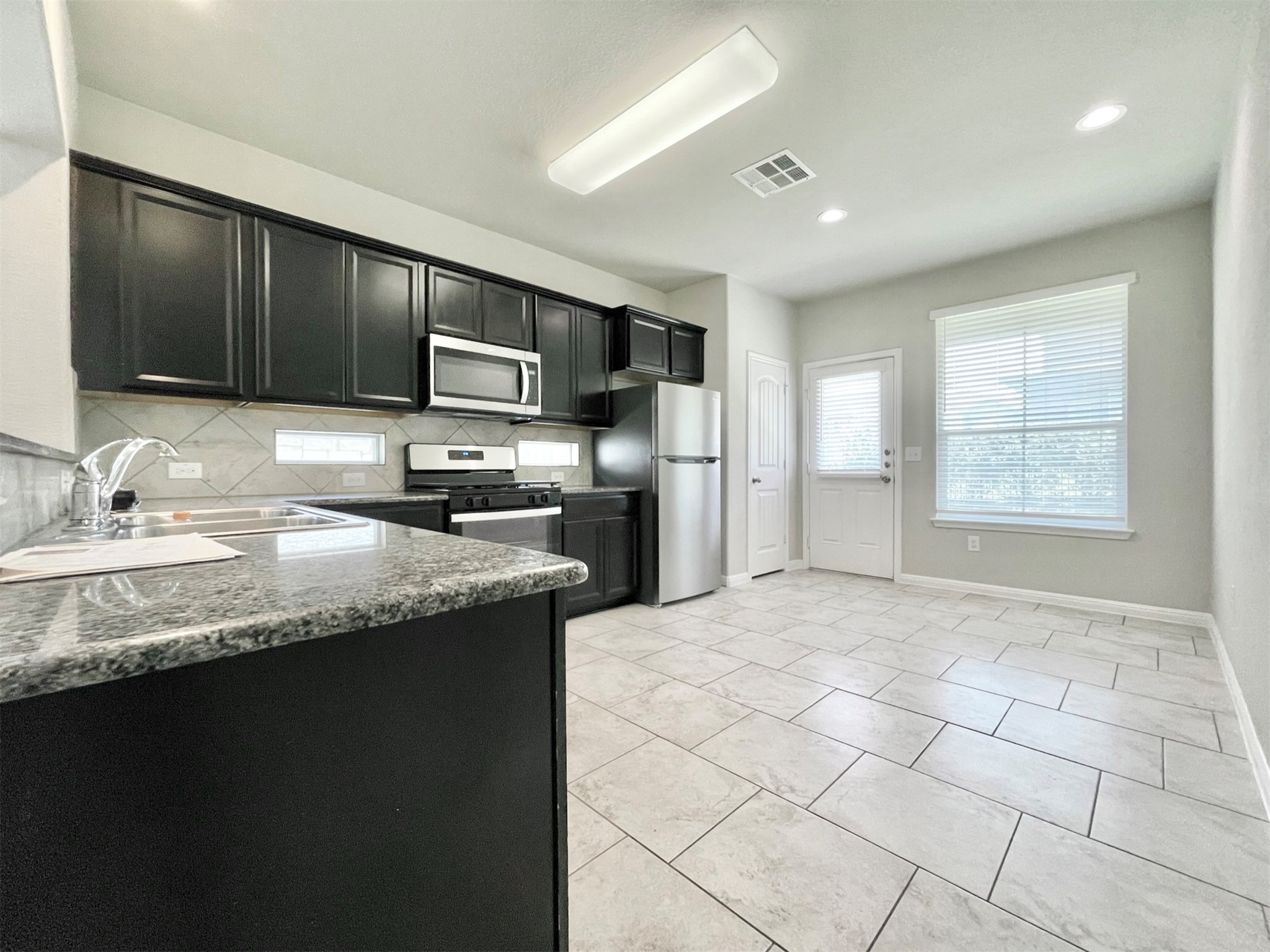 407 Rhetoric Way Pflugerville, TX 78660 - Photo 10 of 38 a kitchen with granite countertop a stove a sink and a microwave