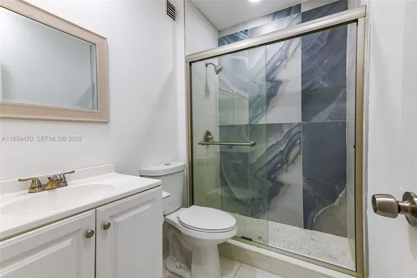 a bathroom with a shower sink vanity and toilet