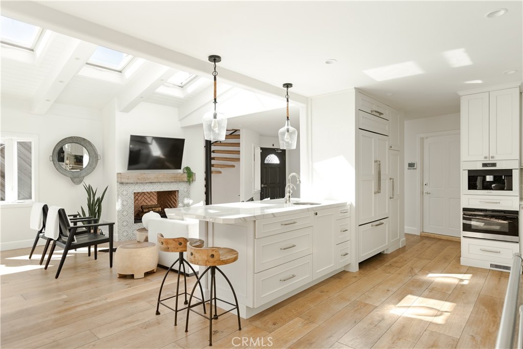 781 Summit Drive Laguna Beach, CA 92651 - Photo 1 of 73 a kitchen with stainless steel appliances kitchen island granite countertop a stove a sink a dining table and chairs with wooden floor