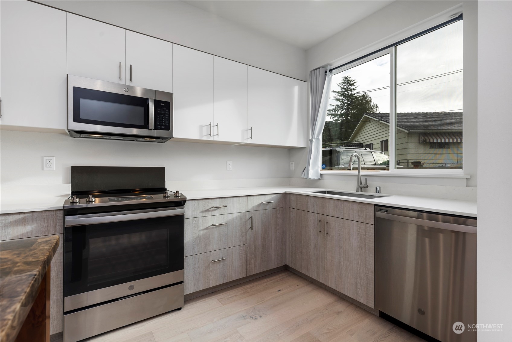 10162 Holman Road Northwest, Unit E Seattle, WA 98133 - Photo 8 of 26 a kitchen with stainless steel appliances a stove sink and microwave