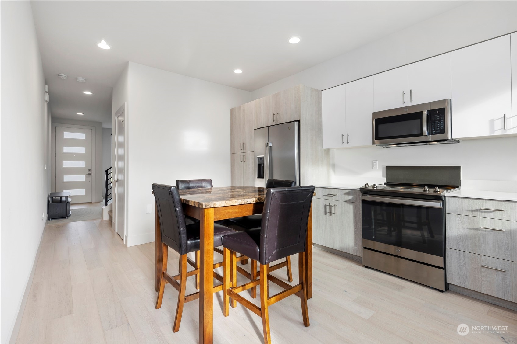 10162 Holman Road Northwest, Unit E Seattle, WA 98133 - Photo 9 of 26 a kitchen with stainless steel appliances kitchen island granite countertop a stove a sink a microwave and a refrigerator