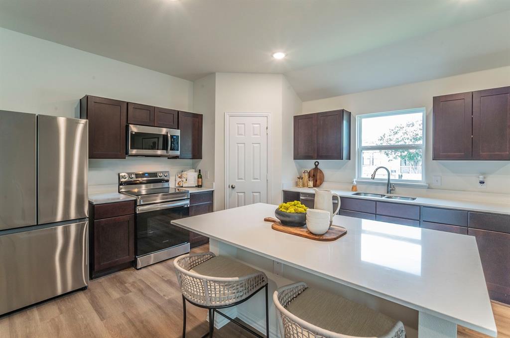 440 Rose Avenue Cleburne, TX 76033 - Photo 6 of 14 a kitchen with a refrigerator a stove a sink and a dining table with wooden floor