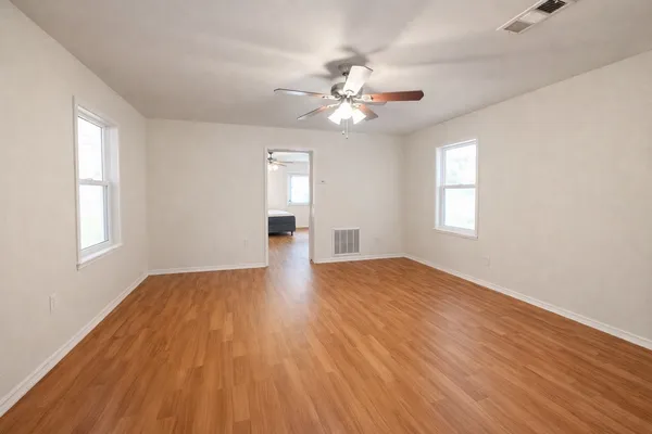 a view of empty room with wooden floor and fan