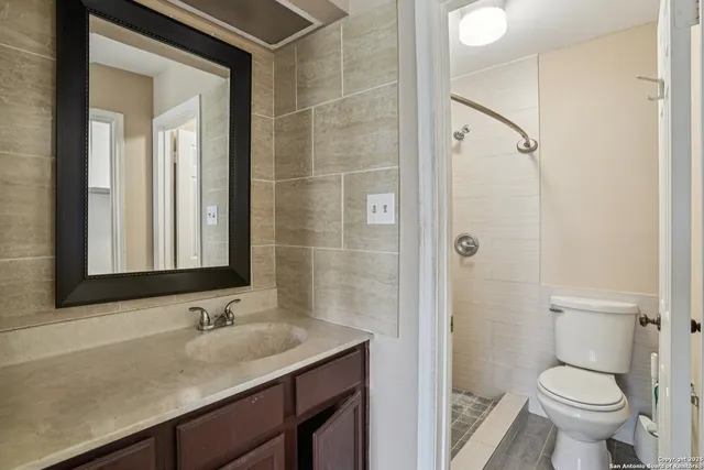 a bathroom with a granite countertop sink toilet and shower