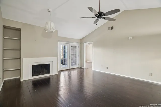 a view of an empty room with a fireplace and a ceiling fan