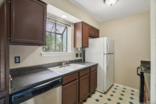 a kitchen with sink a refrigerator and a window