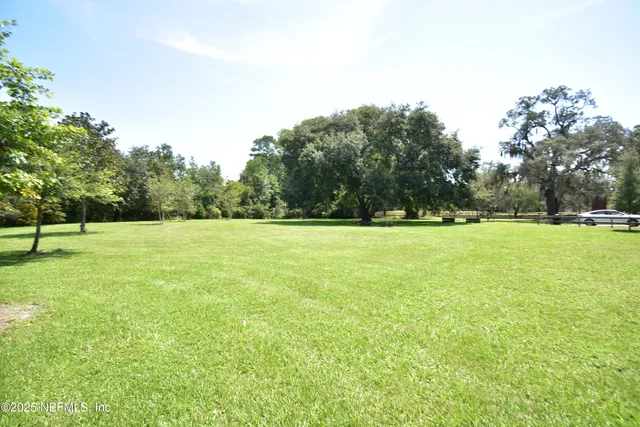 a view of a house with a big yard and palm trees