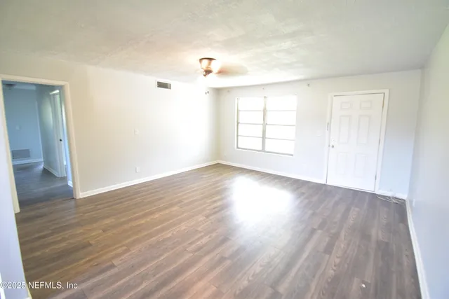 an empty room with wooden floor and windows