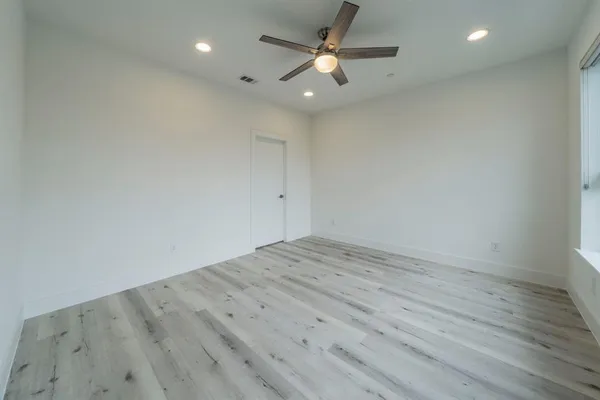 an empty room with wooden floor and a ceiling fan