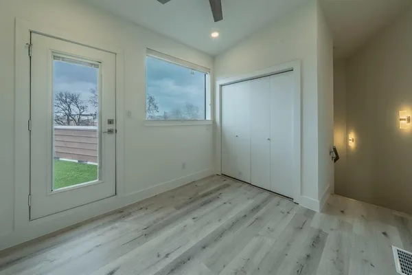 a view of an empty room with wooden floor and a window