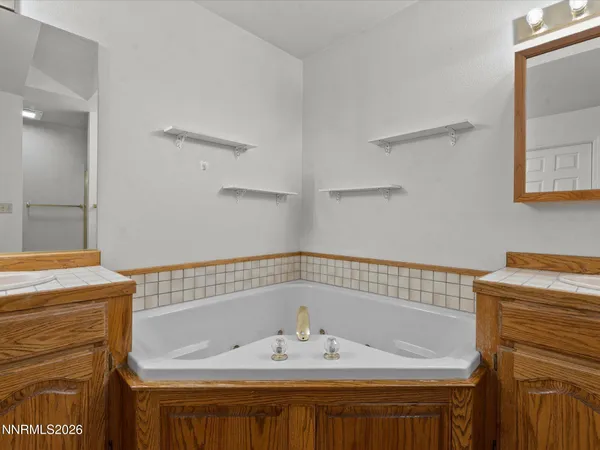 a bathroom with a tub sink double vanity and a mirror