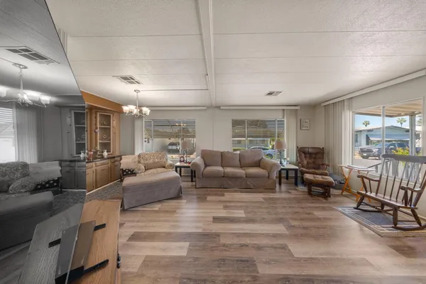 a living room with furniture a chandelier and a view of kitchen