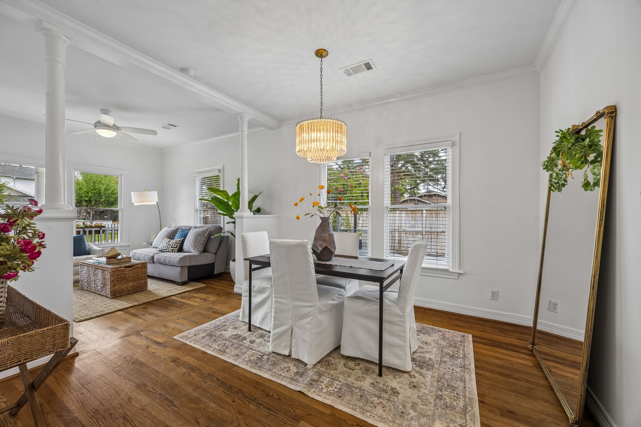812 West 13th Street Houston, TX 77008 - Photo 11 of 29 This photo shows a bright and inviting open-concept living and dining area. It features hardwood floors, large windows, and modern furnishings. The dining space is adorned with a chic pendant light, and the living area includes a comfortable sofa and a ceiling fan for a cozy ambiance.