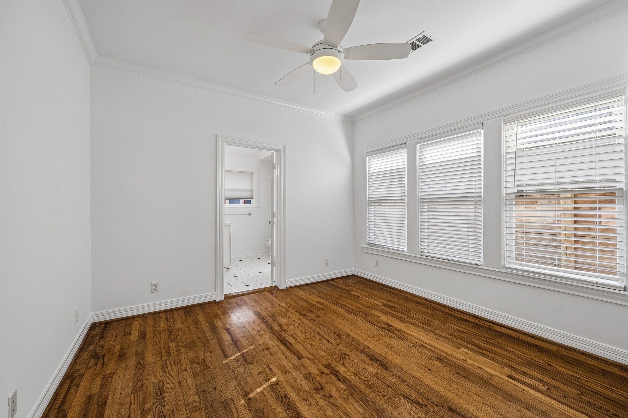 812 West 13th Street Houston, TX 77008 - Photo 16 of 29 Bright room with hardwood floors, large windows with blinds, a ceiling fan, and an adjacent tiled area, perfect for a bedroom or office space.