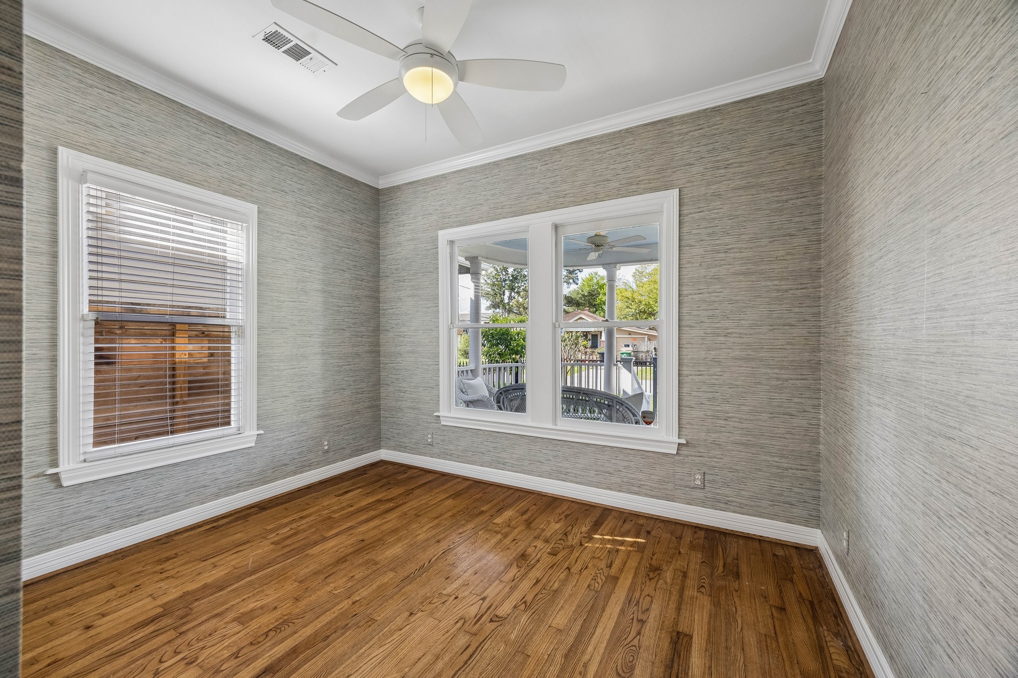 812 West 13th Street Houston, TX 77008 - Photo 20 of 29 This room features hardwood floors, a ceiling fan, and large windows with views of a porch and greenery, creating a bright and inviting space.