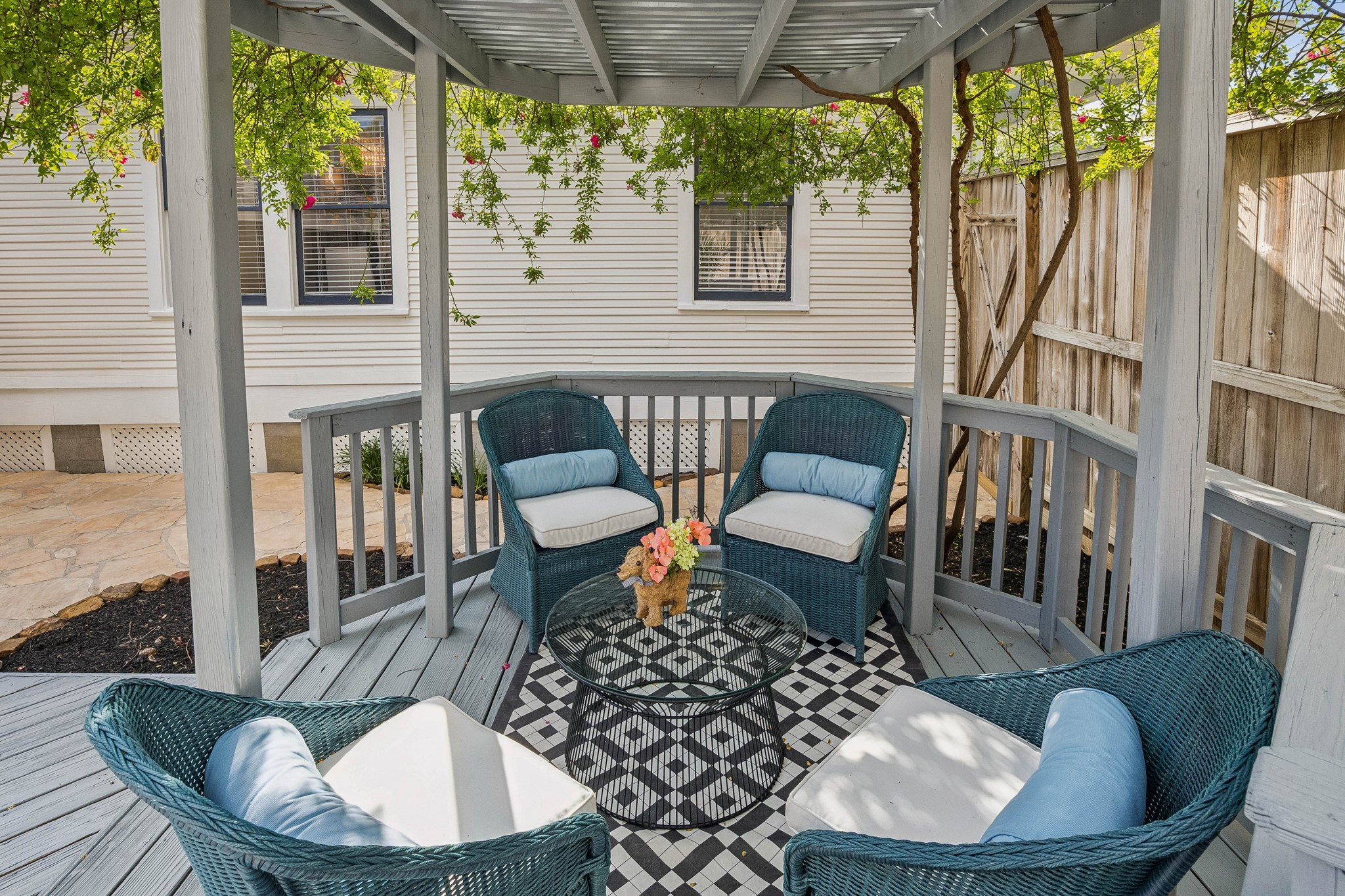812 West 13th Street Houston, TX 77008 - Photo 27 of 29 Charming backyard gazebo with a cozy seating area featuring wicker chairs and a patterned rug. Surrounded by greenery and enclosed by a wooden fence, perfect for relaxing or entertaining.