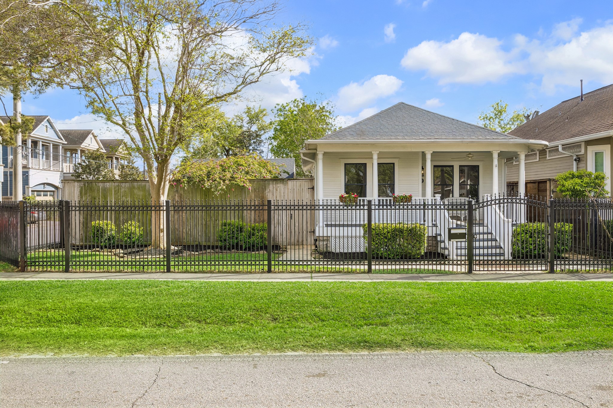 812 West 13th Street Houston, TX 77008 - Photo 6 of 29 Charming single-story home with a welcoming front porch, surrounded by a neatly maintained yard and enclosed by a decorative metal fence. The house features a traditional design, mature trees, and a cozy outdoor space ideal for relaxing.