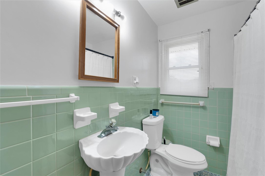 1815 Pearman Dairy Road Anderson, SC 29625 - Photo 19 of 35 A vibrant bathroom features jade green tiled walls, a window for natural light, and classic fixtures.