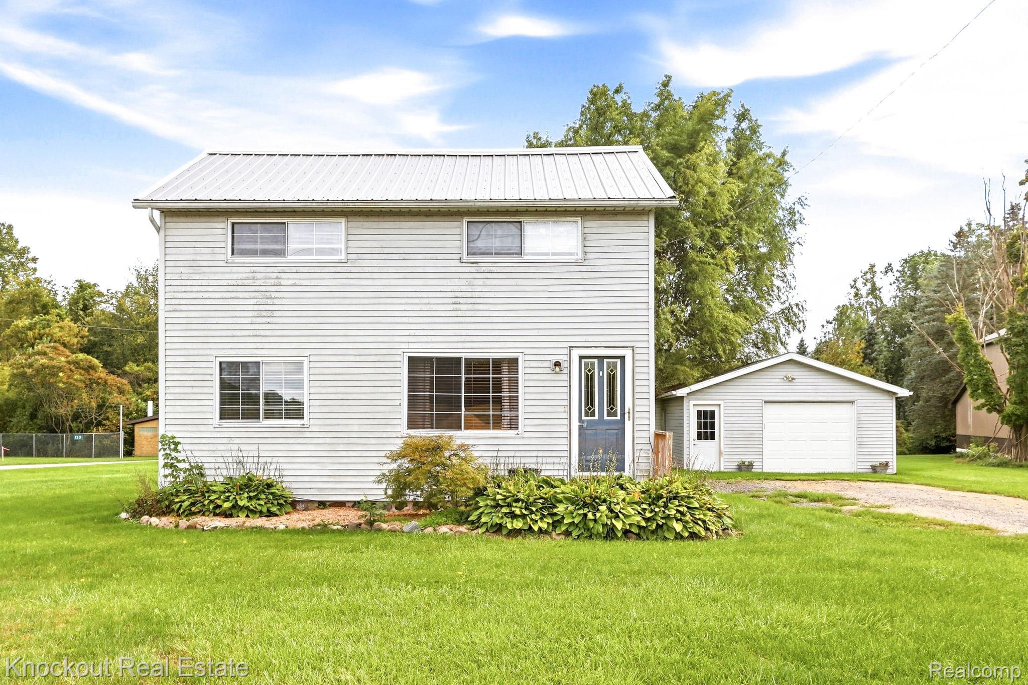 8771 Van Cleve Road Vassar, MI 48768 - Photo 2 of 44 Two-story residence with a metal roof, light-colored siding, and a detached single-car garage