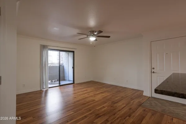 an empty room with wooden floor fan and windows