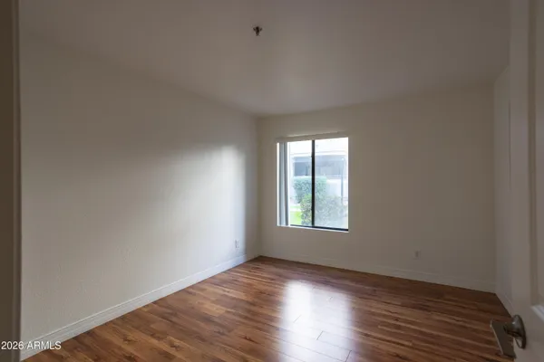 a view of an empty room with wooden floor and a window