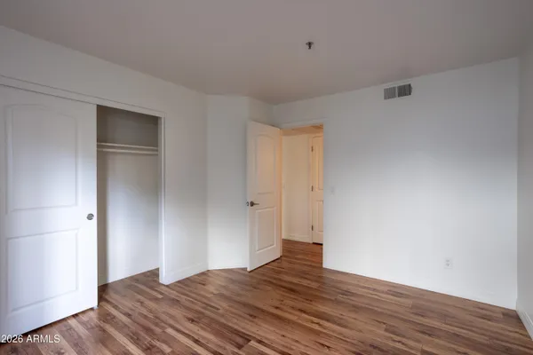 a view of an empty room with wooden floor and closet