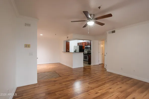 a view of an empty room with kitchen and a ceiling fan