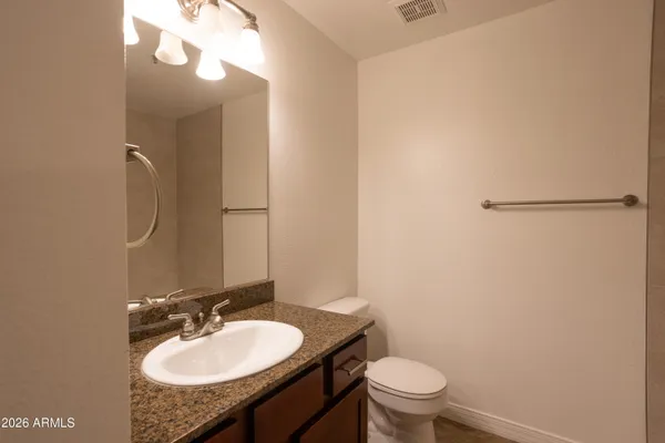 a bathroom with a granite countertop sink toilet and a mirror